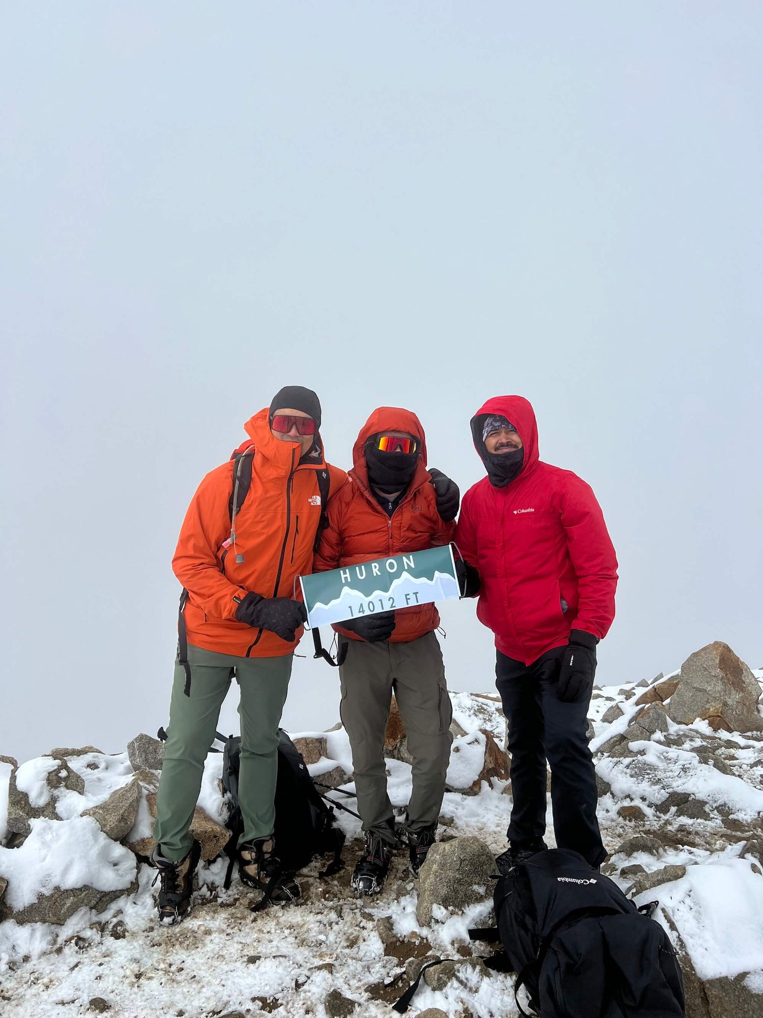 Group of high altitude hikers at the top of Mount Huron with a Summiter Mountain Flag