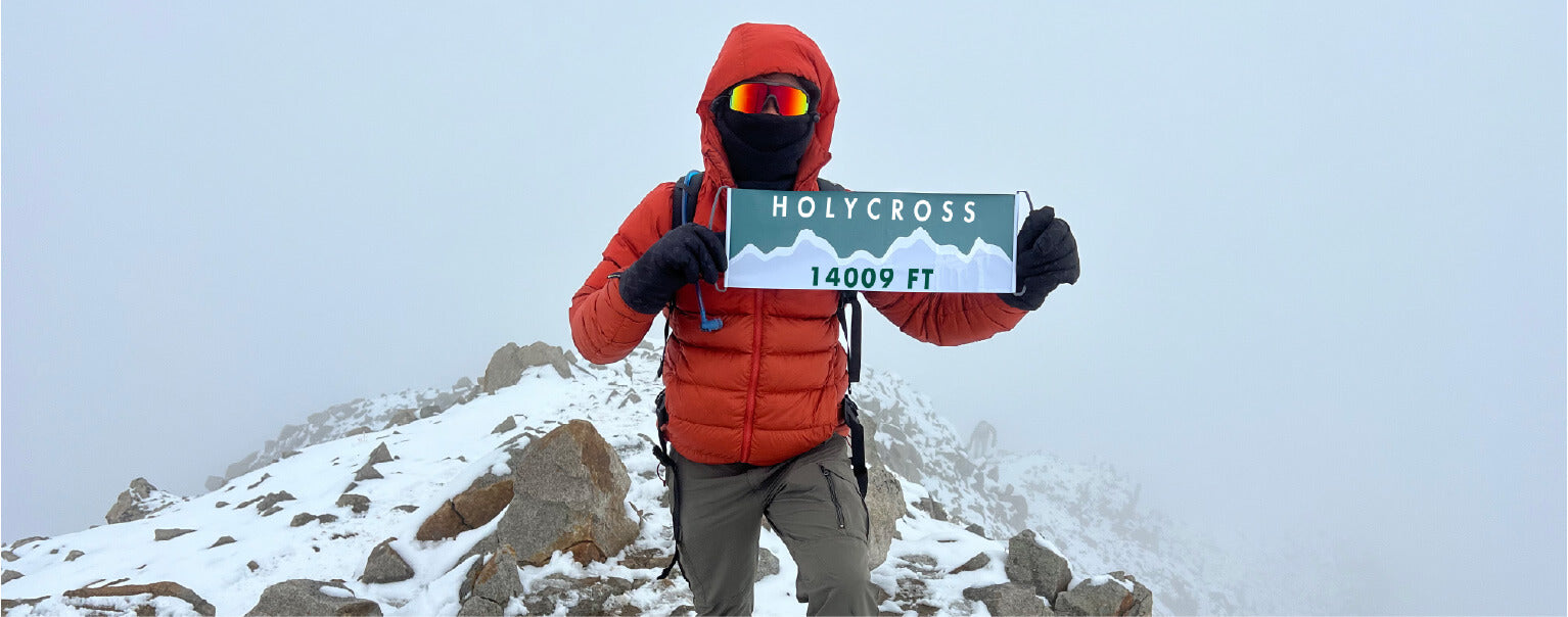 Hiker on the top of Mount Holycross weather resistant mountain flag by Summiter