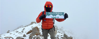 Hiker on the top of Mount Holycross weather resistant mountain flag by Summiter